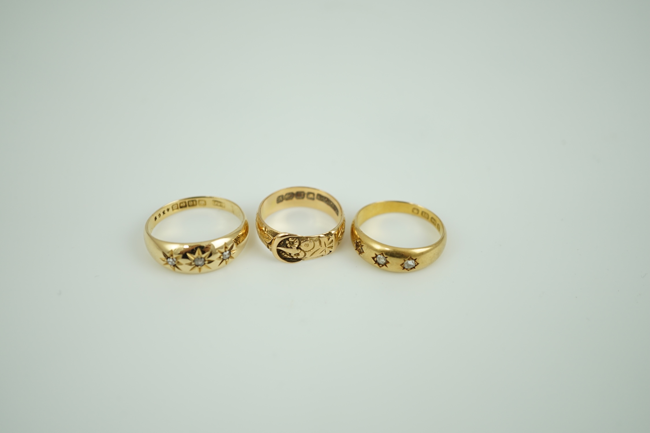 A Victorian 18ct gold buckle ring, size K/L, a Victorian 18ct gold and gypsy set three stone diamond ring (stone missing) and a later 18ct gold and gypsy set three stone diamond ring